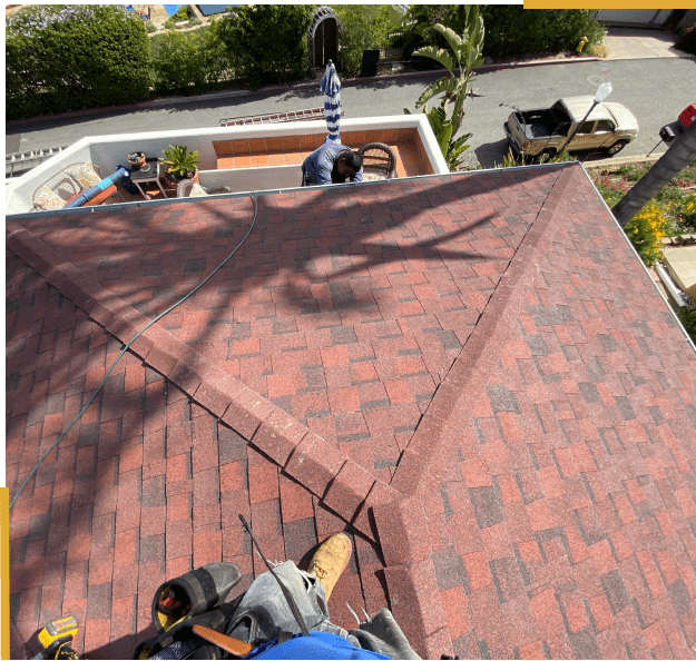 Worker on red shingled roof, repairing.